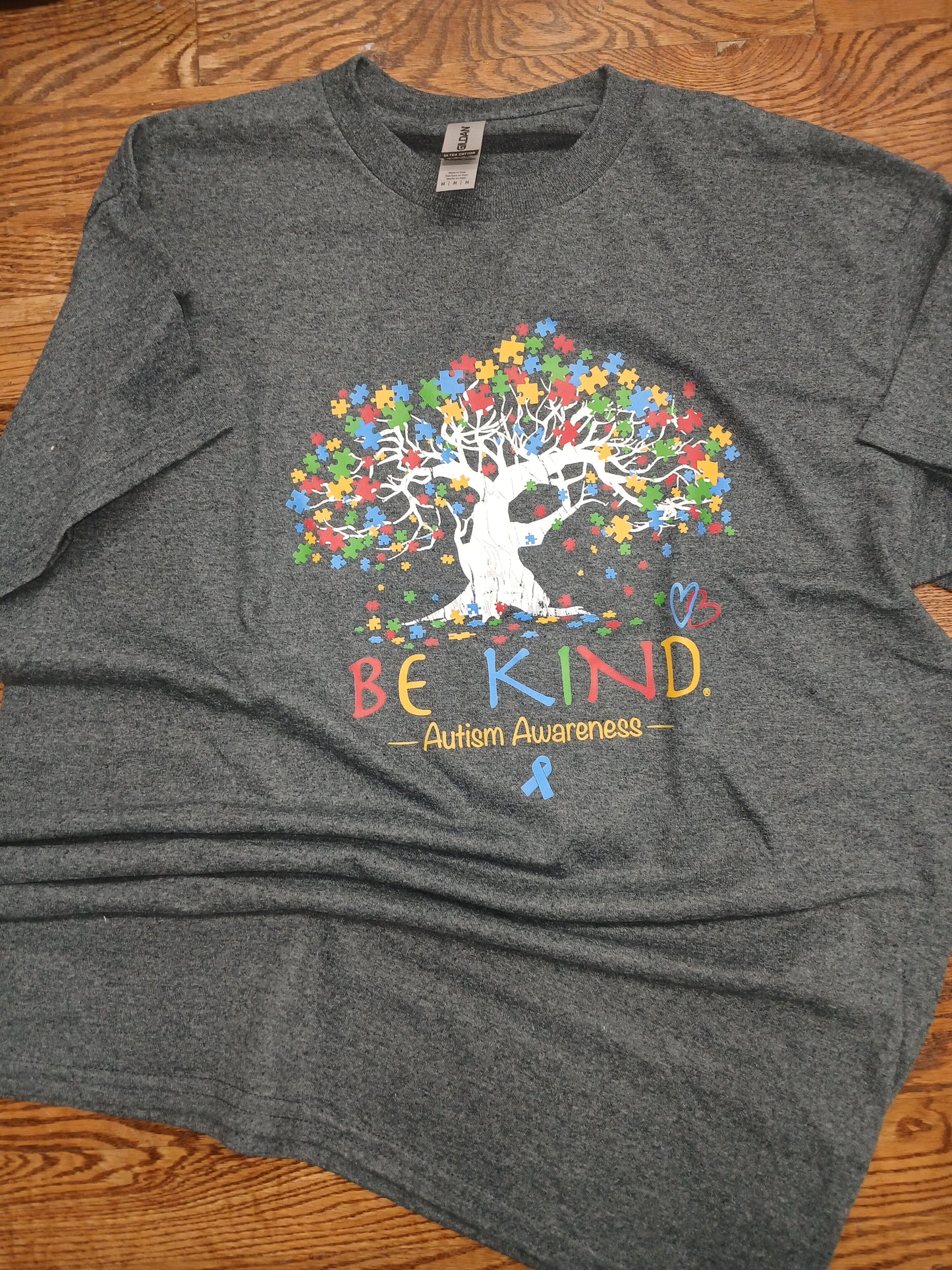 Gray t-shirt with a colorful design of a tree with text Be Kind