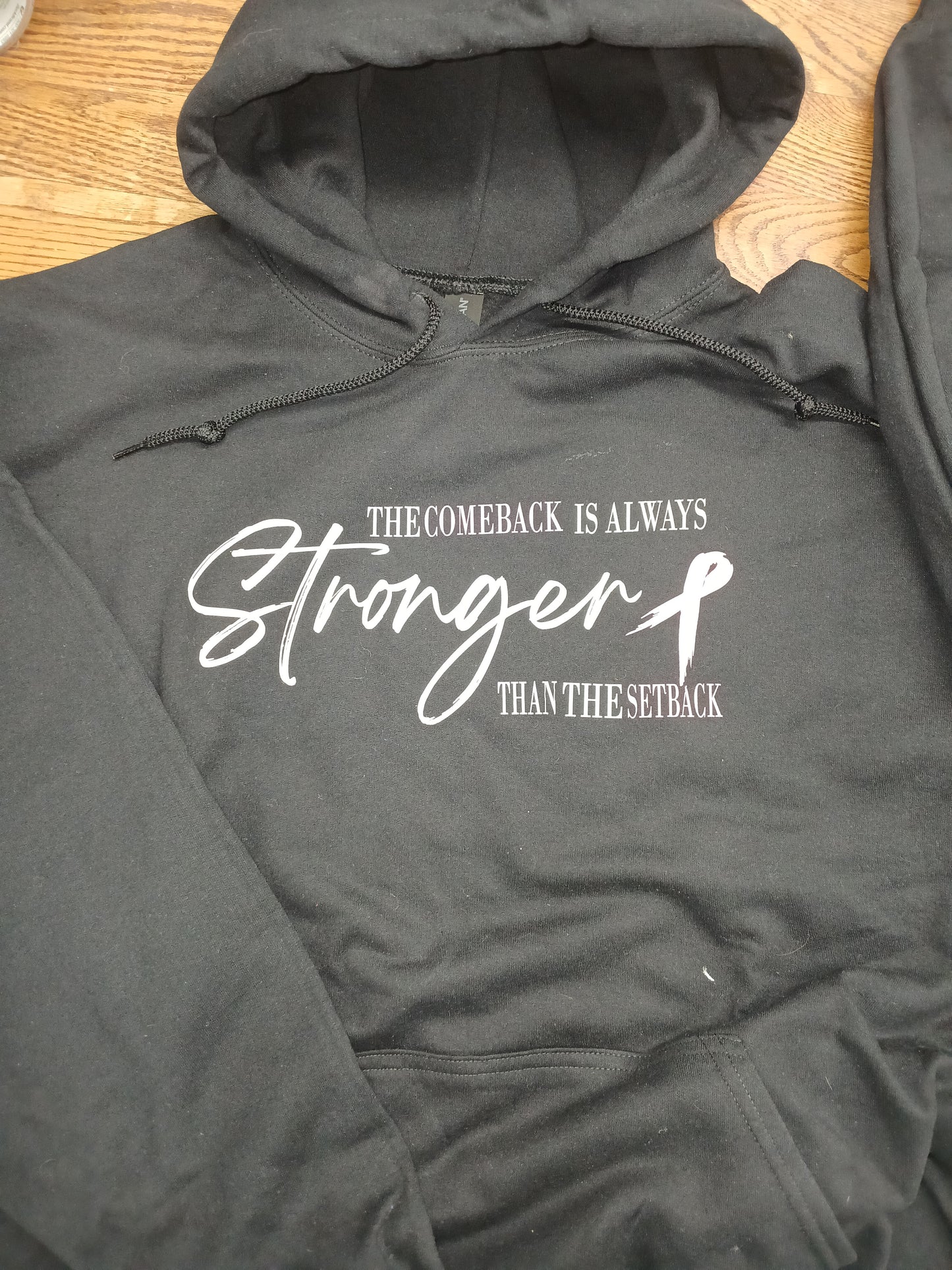 Charcoal hoodie with white and pink text the comeback is always stronger than the setback