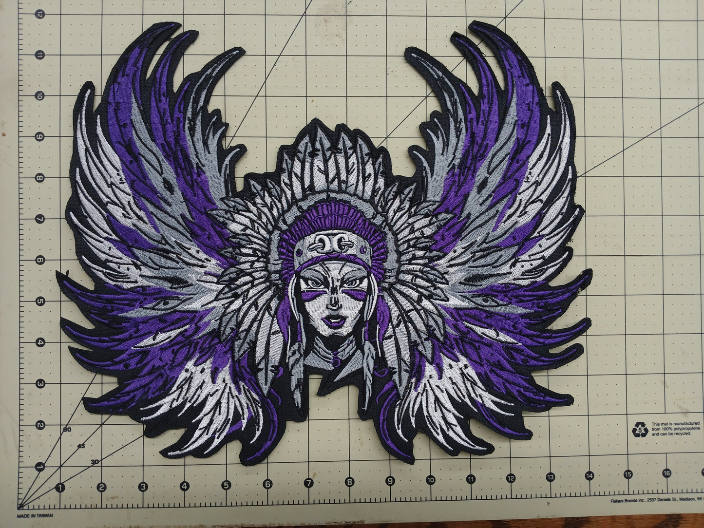 Decorative patch with purple and white wings on a grid background