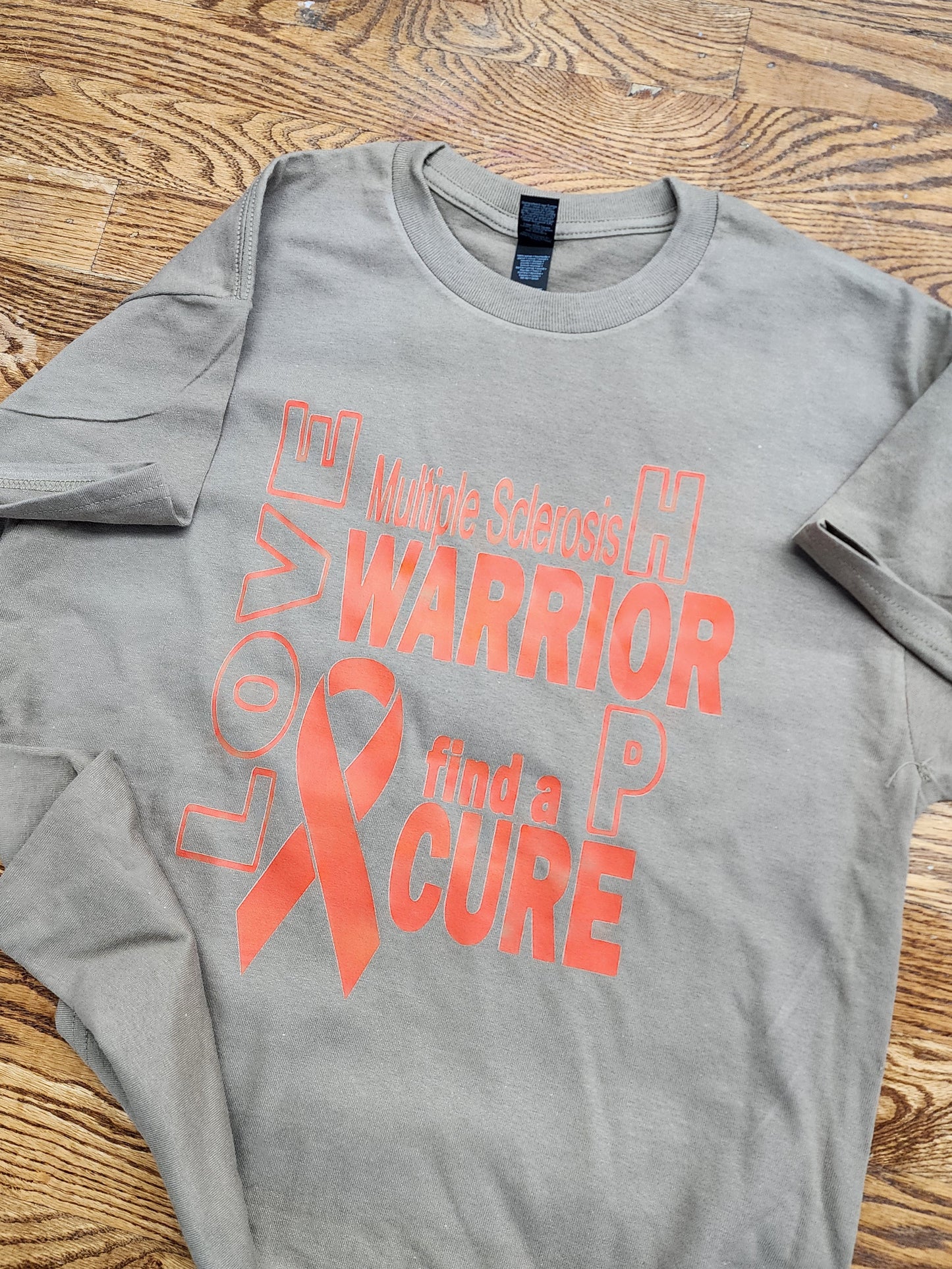 Light brown t-shirt with orange text and ribbon supporting Multiple Sclerosis support for a cure.