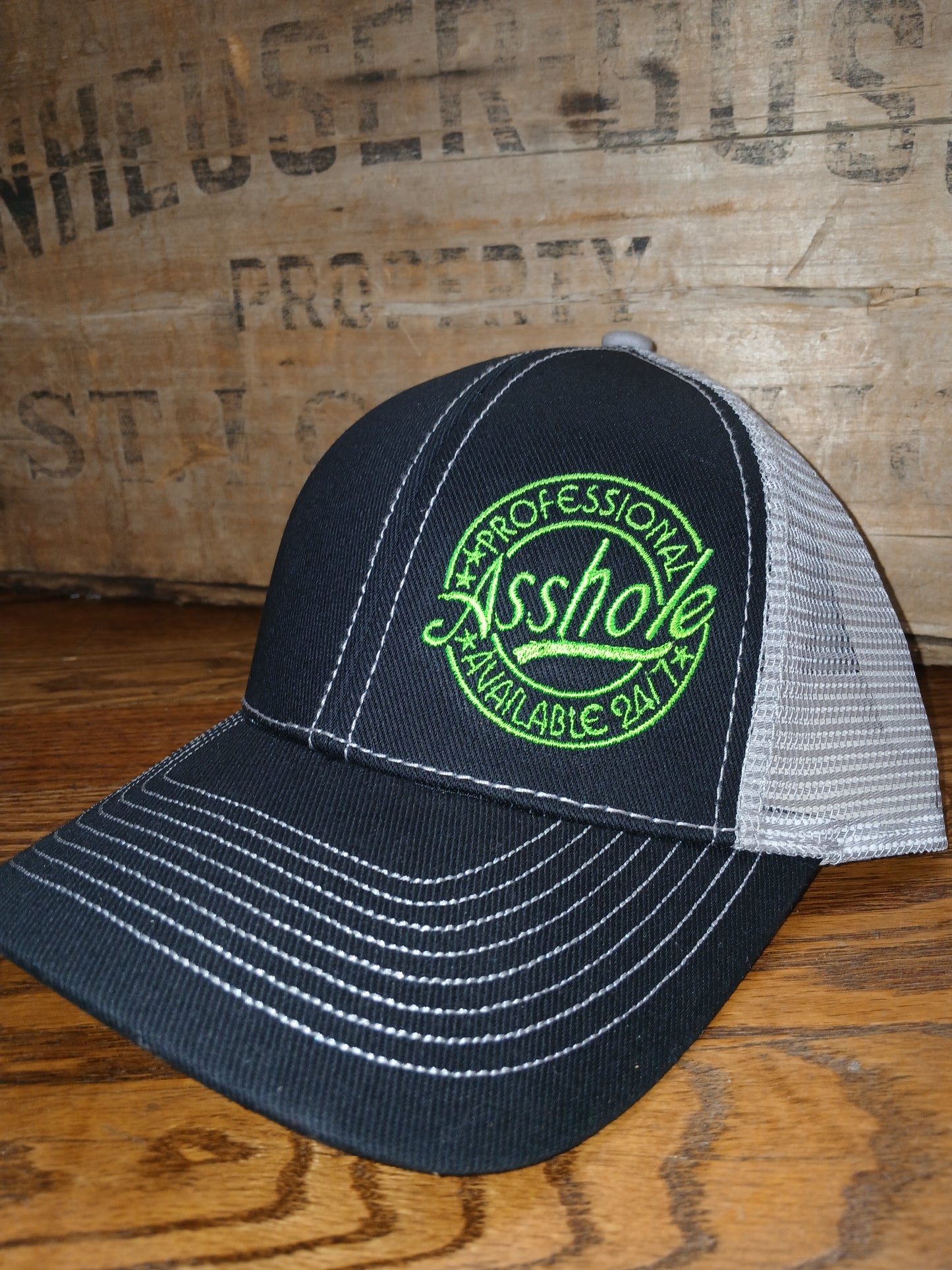 Richardson 112 Black cap with green text "Professional Asshole Available 4/7"