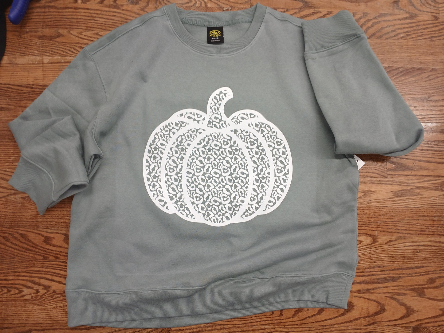 Sage green sweatshirt with a white pumpkin design 